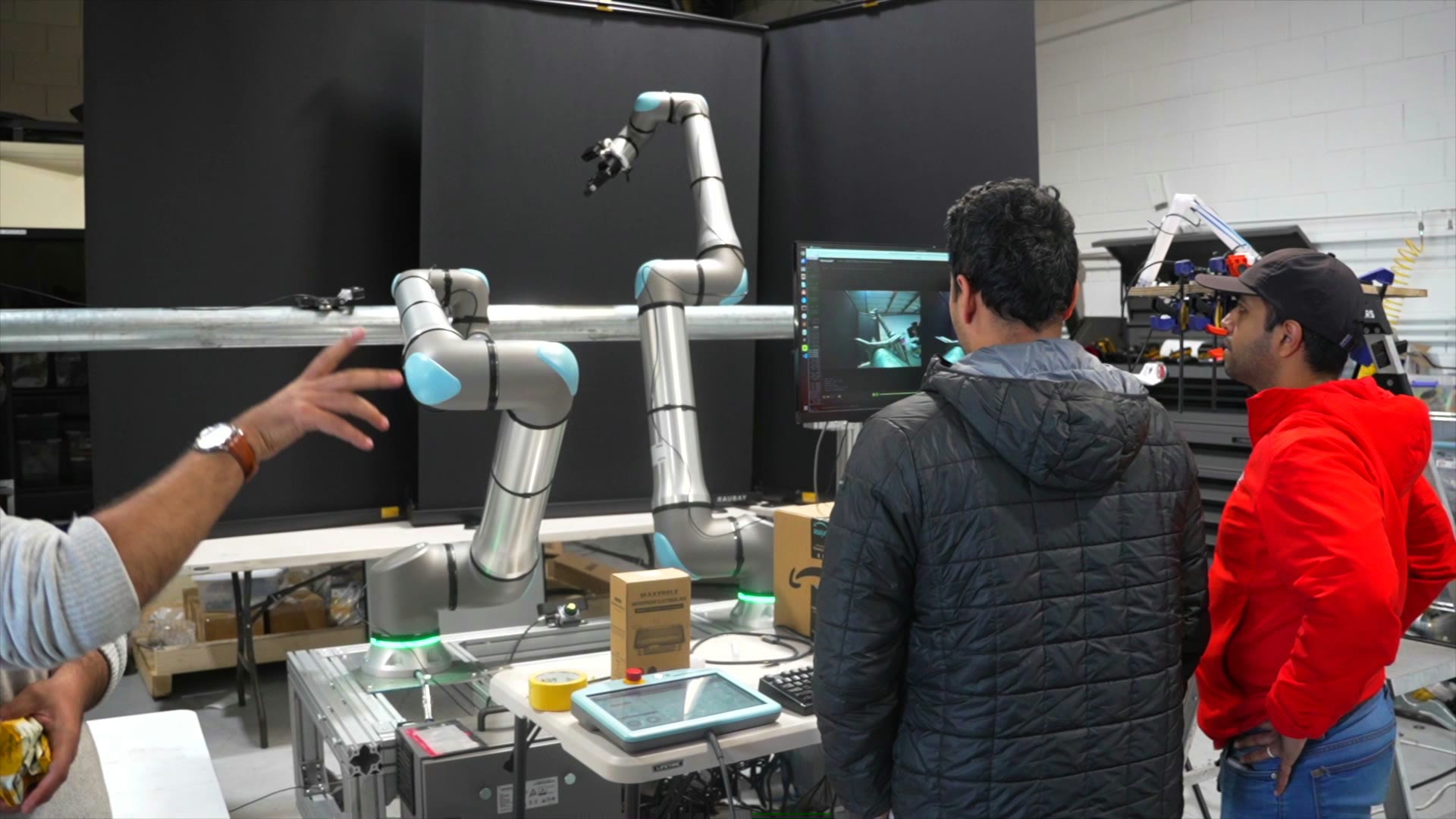 A Gritt robotic arm on a workbench in the lab, team members observing a perception view on a monitor and discussing